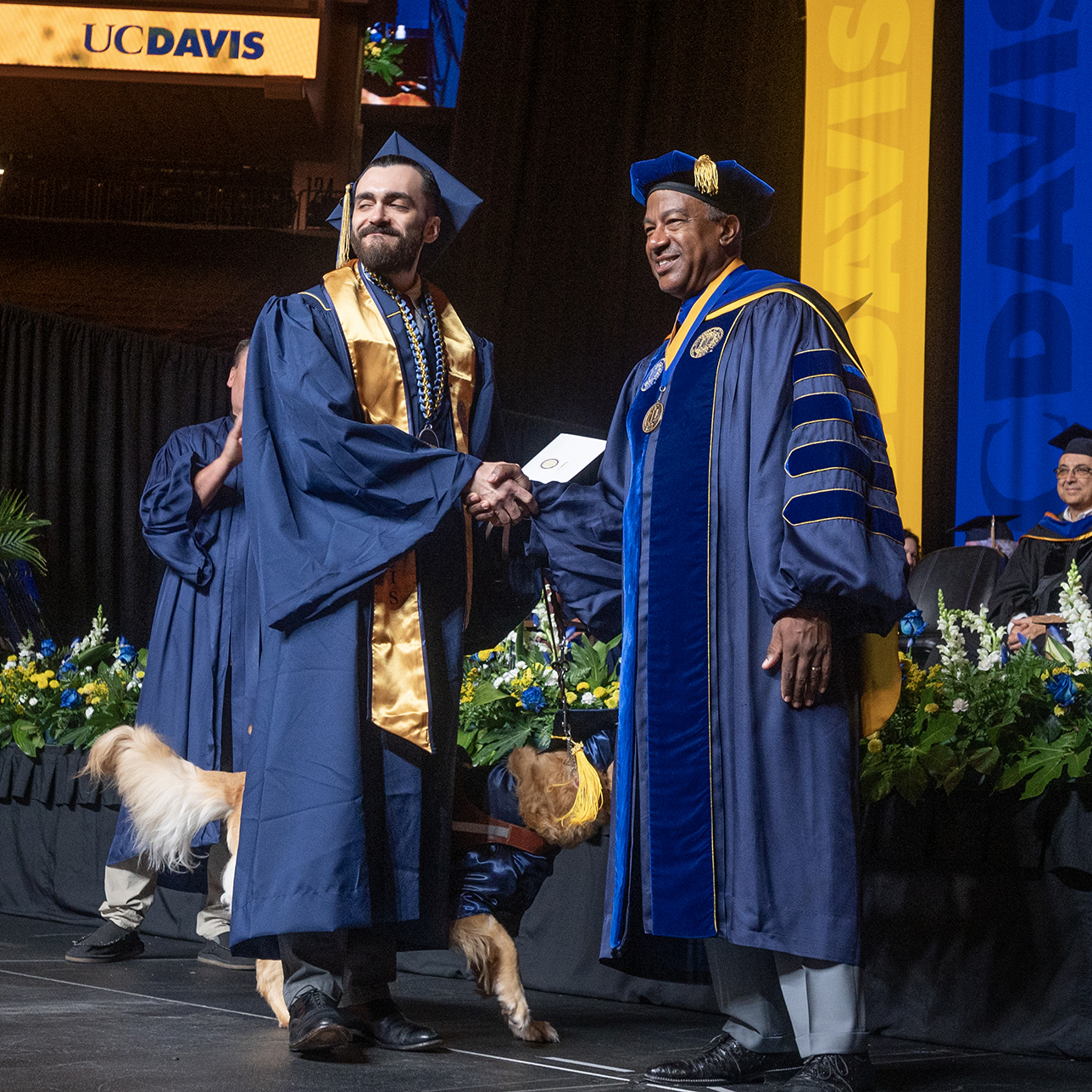 A student shaking hands with UC Davis Chancellor on the commencement stage.